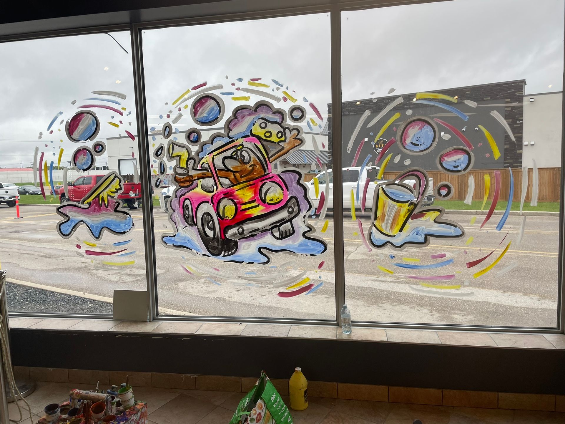 A window with a cartoon drawing of a man driving a car.