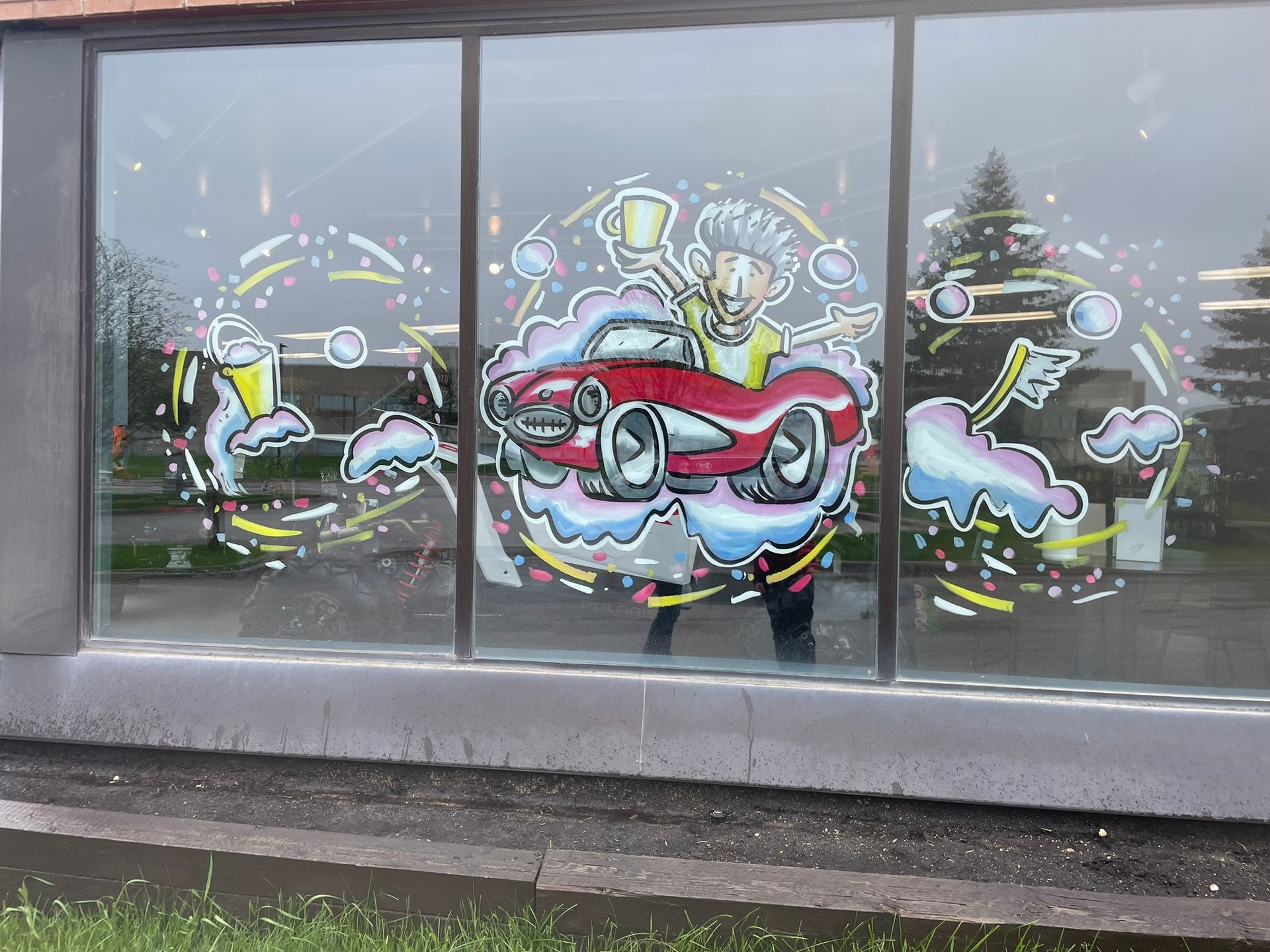 There is a painting of a car on the window of a building.
