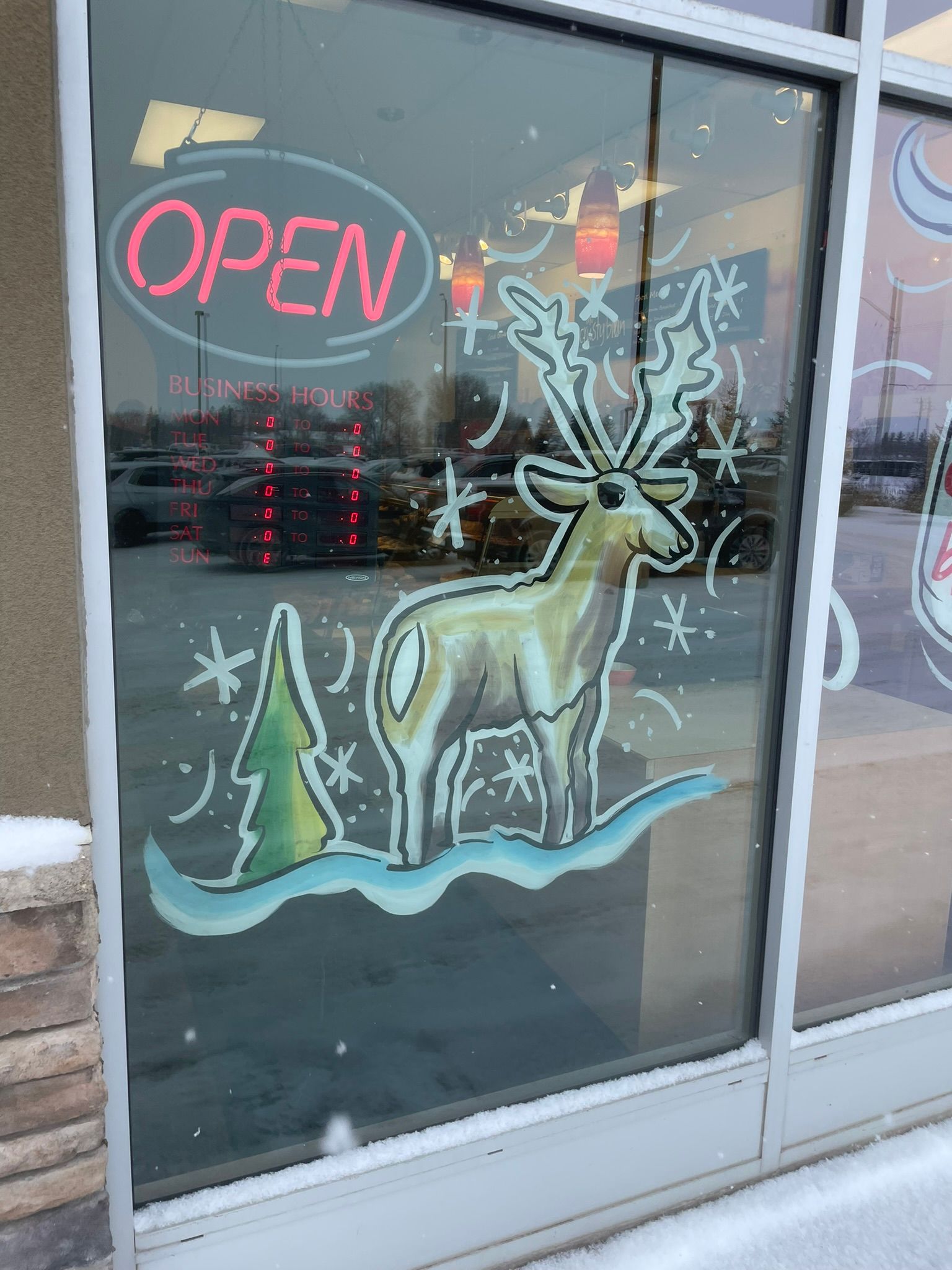 A window with a deer and a sign that says open