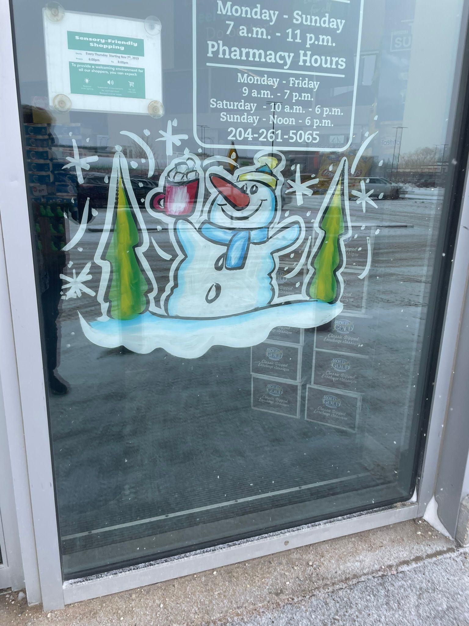 A snowman is painted on the window of a pharmacy.