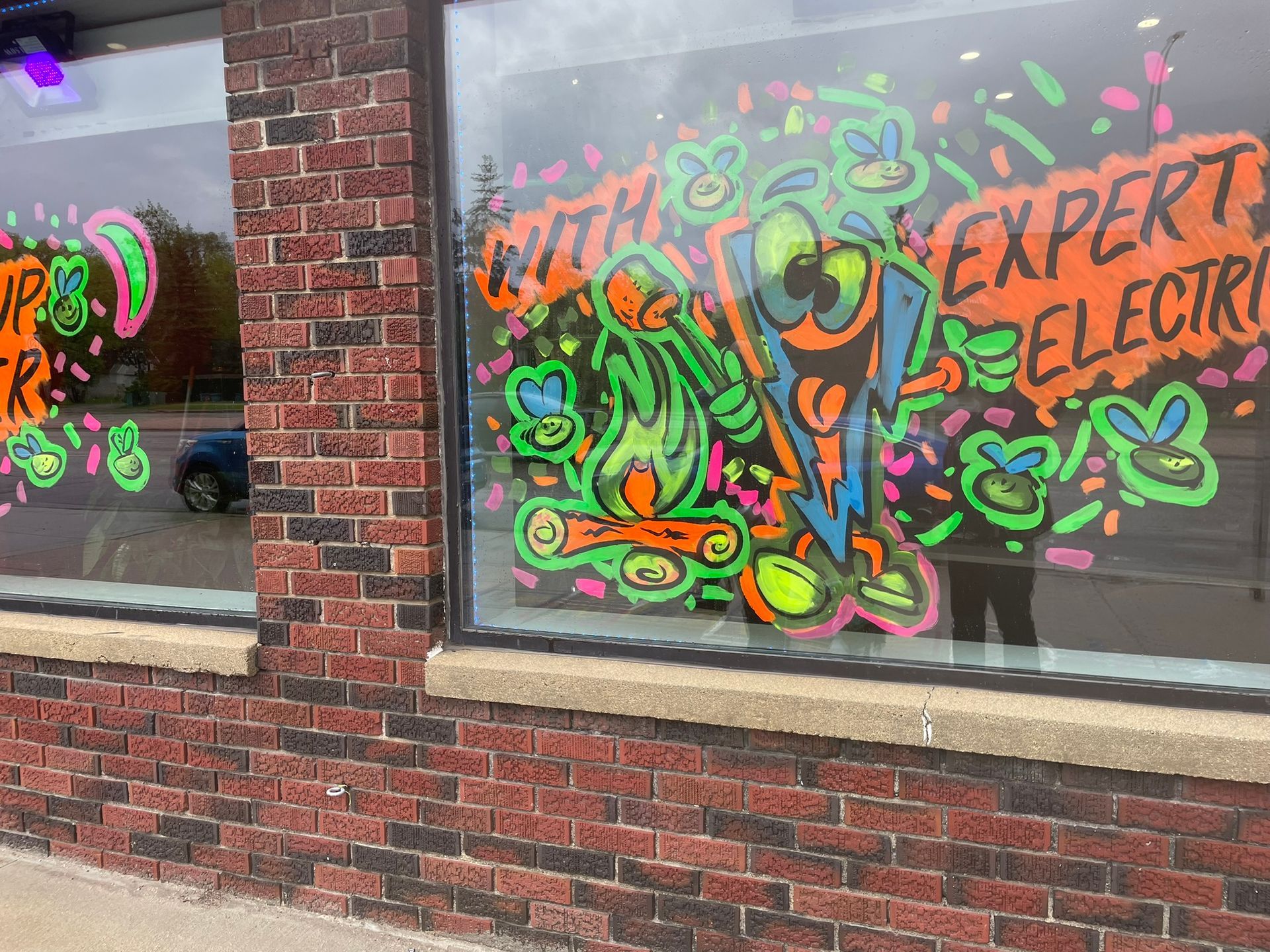A brick building with a neon drawing on the window.
