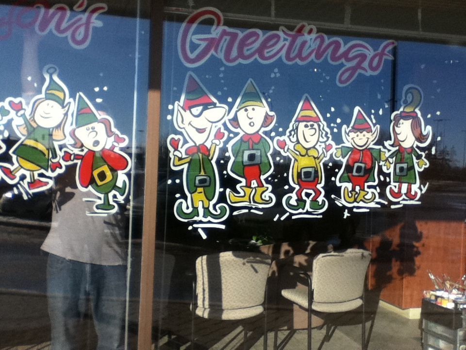 A window with christmas elves and the words greetings on it