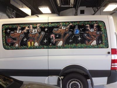 A white van with a painting of reindeer on the window
