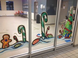 A window with a gingerbread man , candy canes and a christmas tree painted on it