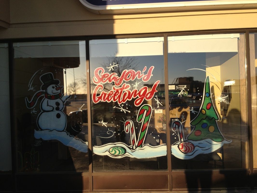 A window with a snowman candy cane and christmas tree painted on it