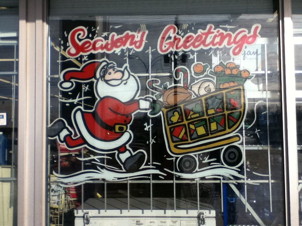 A window with a drawing of santa carrying a shopping cart and the words seasons greetings