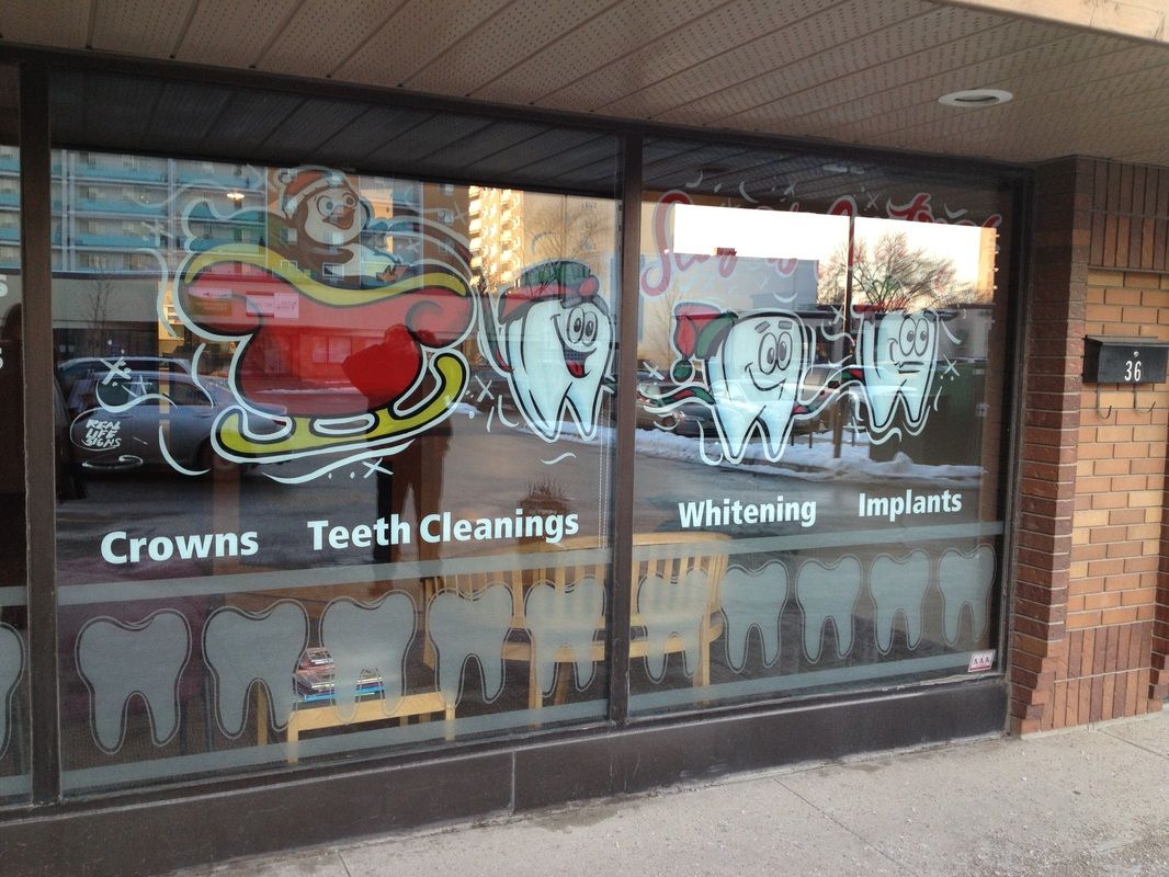 A window of a dental office advertising crowns teeth cleanings and whitening
