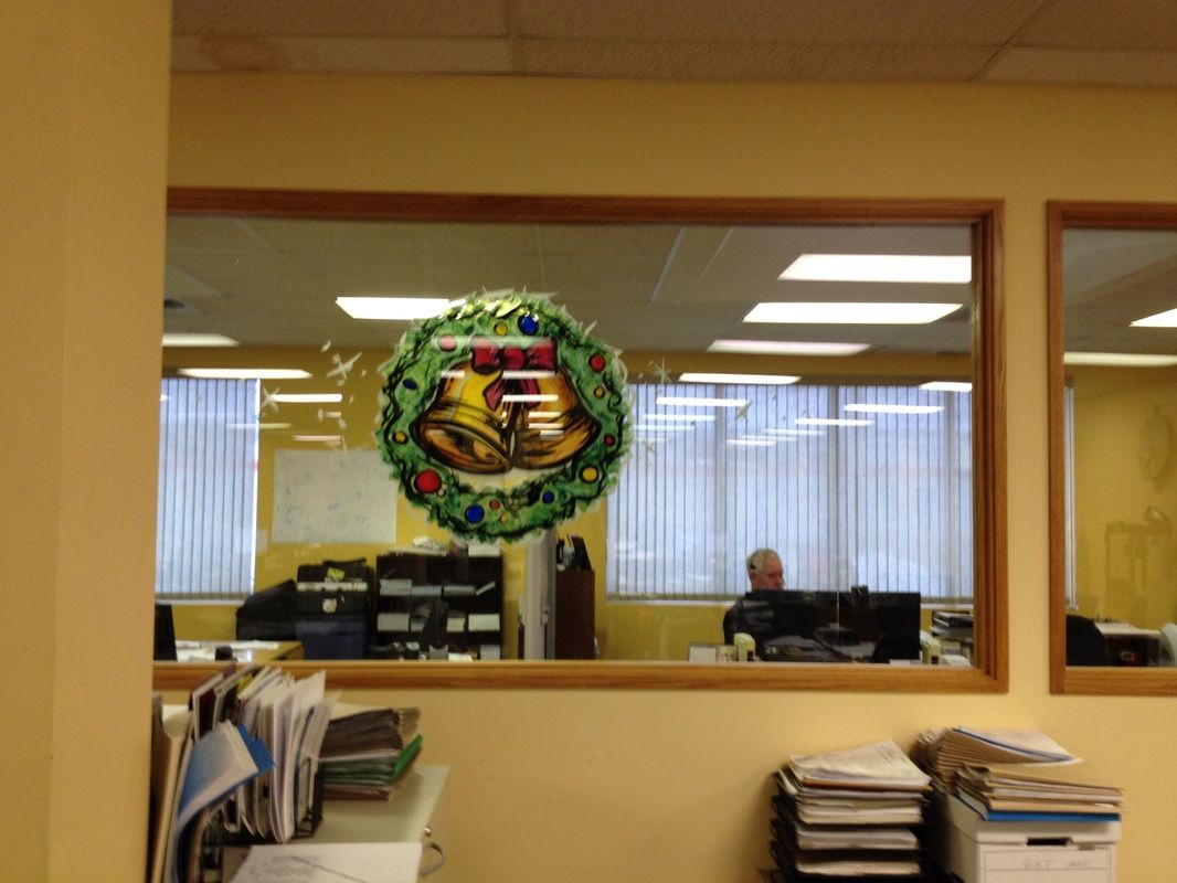 A christmas wreath hangs from a window in an office