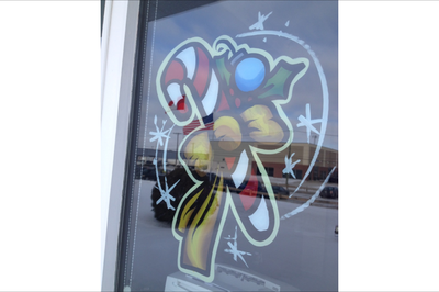 A drawing of a candy cane with a bow on a window.