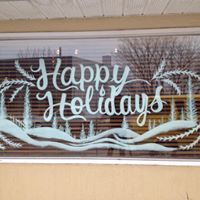 A window with the words `` happy holidays '' painted on it.