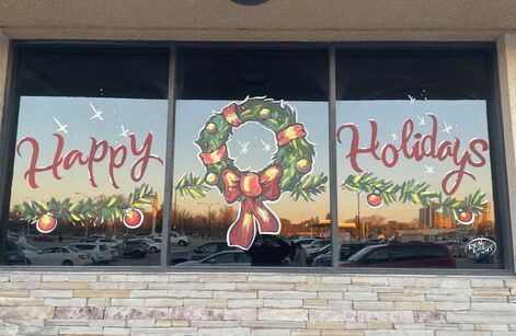 A window with a christmas wreath and the words `` happy holidays '' painted on it.