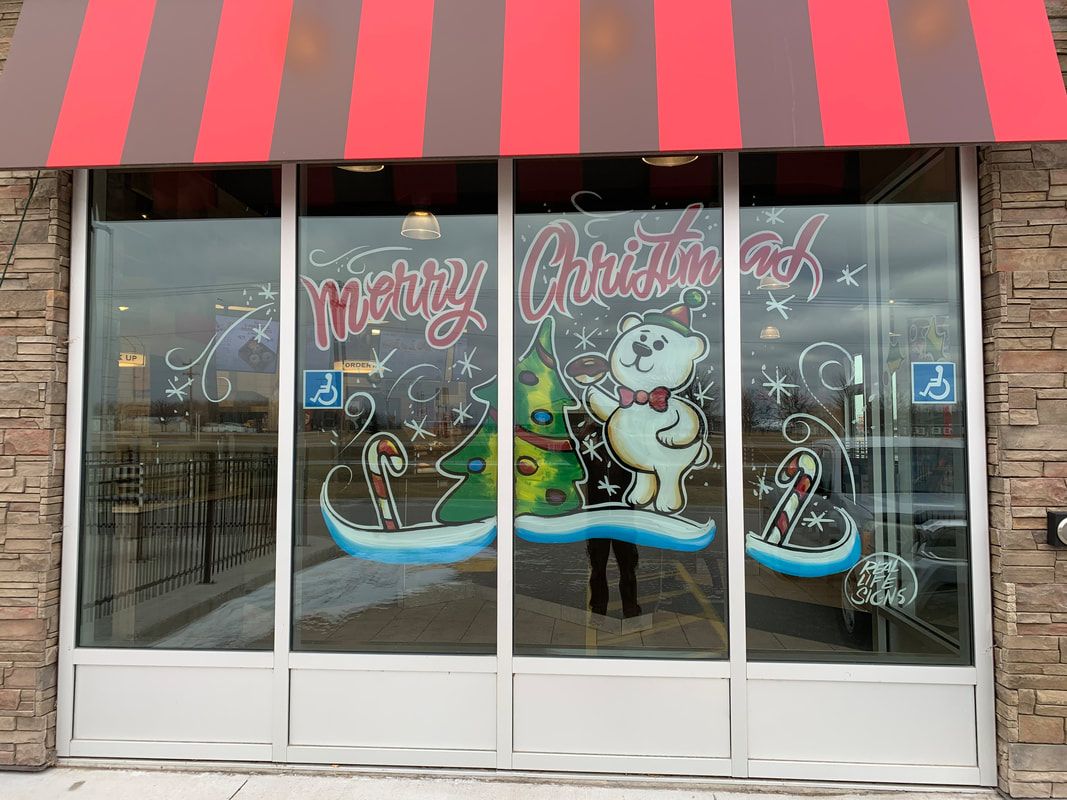 A store front with a red and white awning and christmas decorations on the windows.