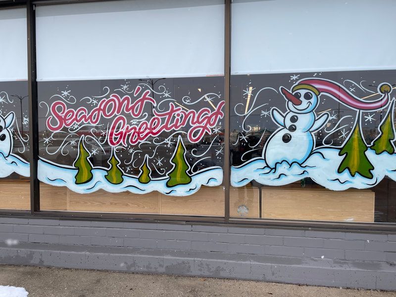 A window with a snowman and trees painted on it