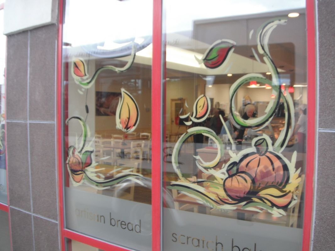A window with a painting of pumpkins and leaves on it