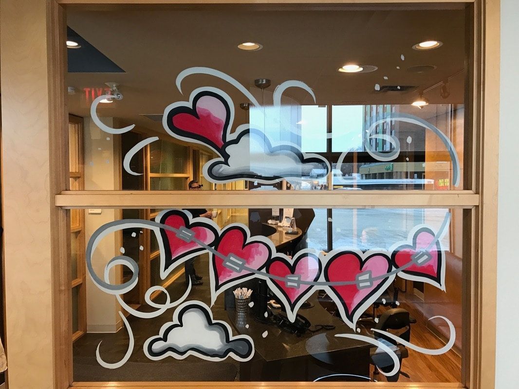 A window with hearts and clouds painted on it