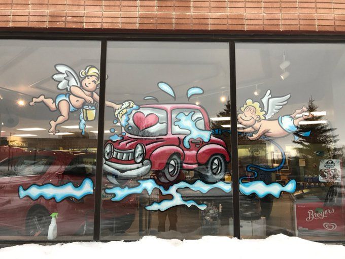 A car is being washed by cupids in a window.