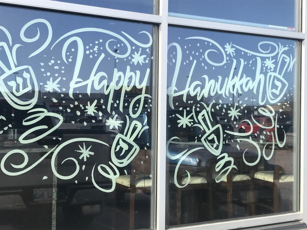 A window with the words `` happy hanukkah '' written on it.
