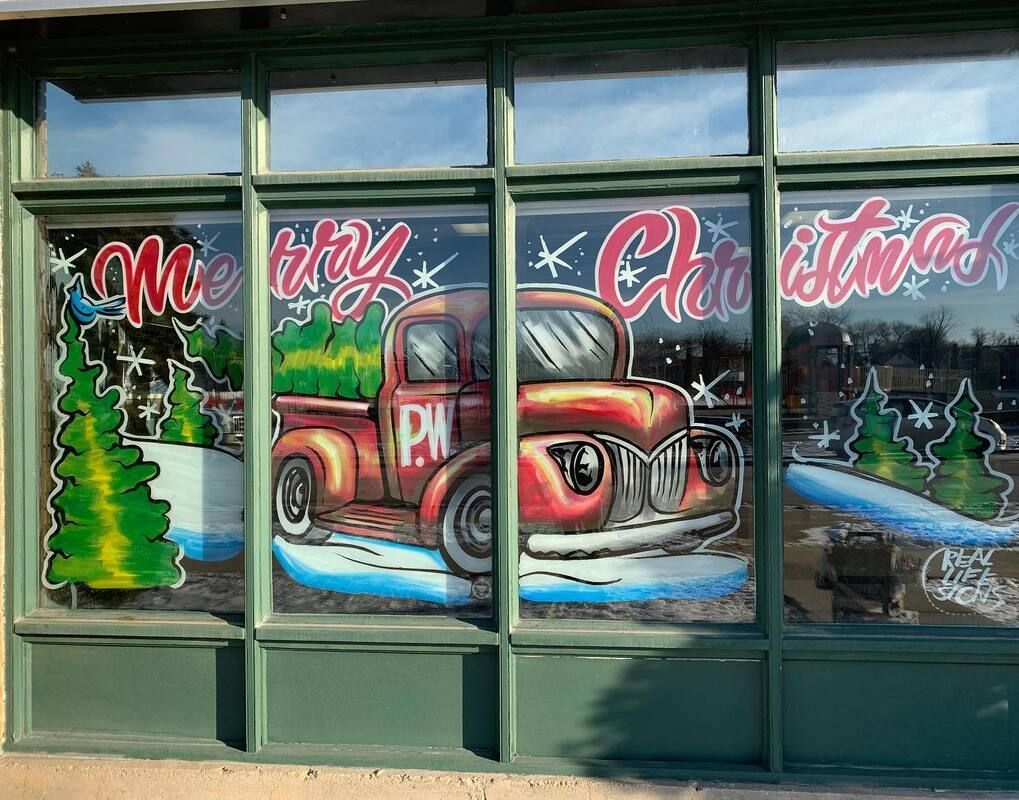 A window with a red truck and christmas trees painted on it