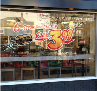 A window with a sign that says 6 steak and cheese only $ 3.99