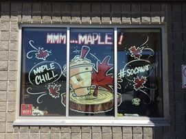 A window with a drawing of a cup of coffee and a maple leaf on it.