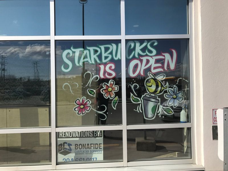 A starbucks is open sign is painted on a window.