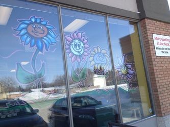 A window with flowers painted on it and a car parked in front of it.