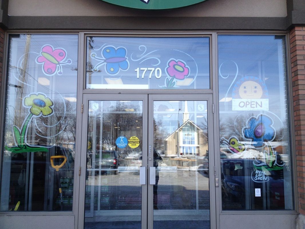 The front door of a store with flowers painted on the windows.