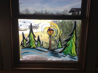 A window with a painting of trees and a lamp on it.