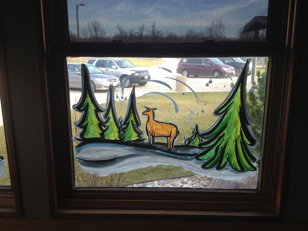 A window with a deer and trees painted on it