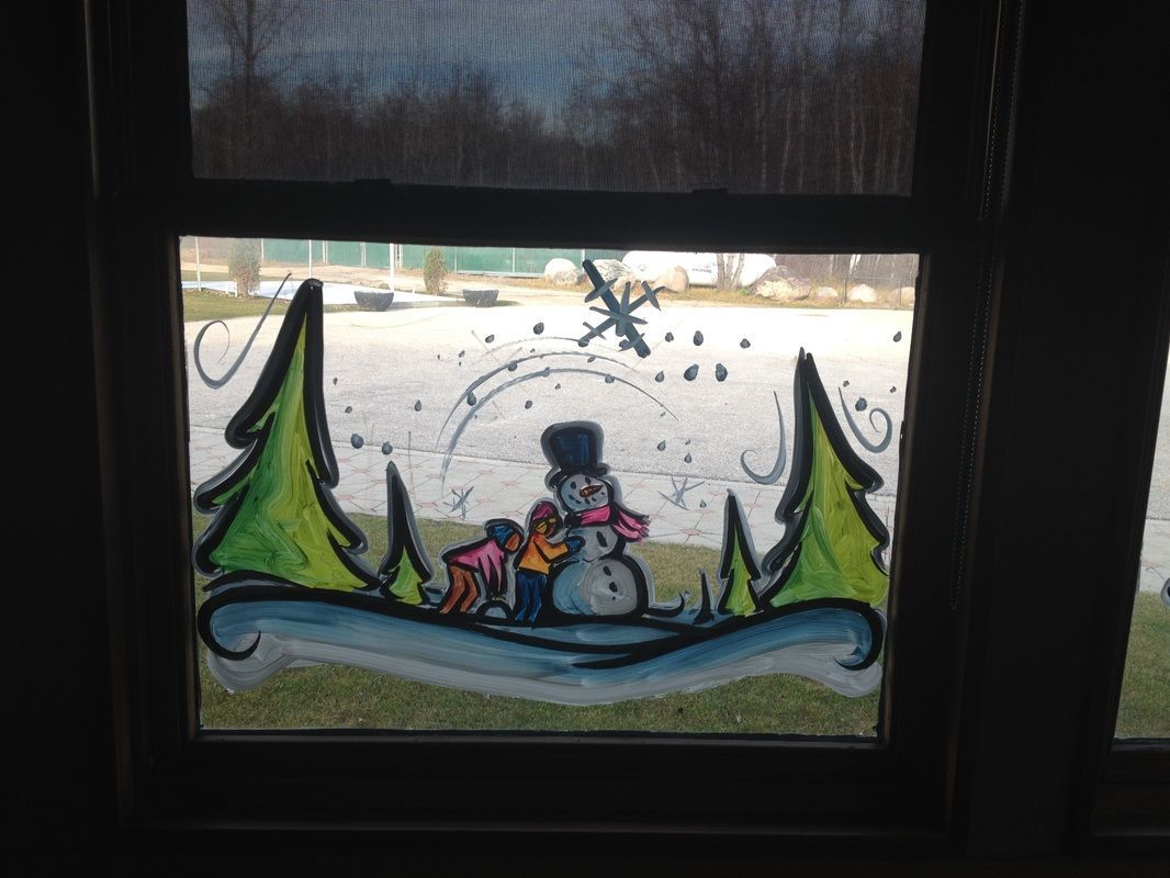 A window with a snowman and trees painted on it.
