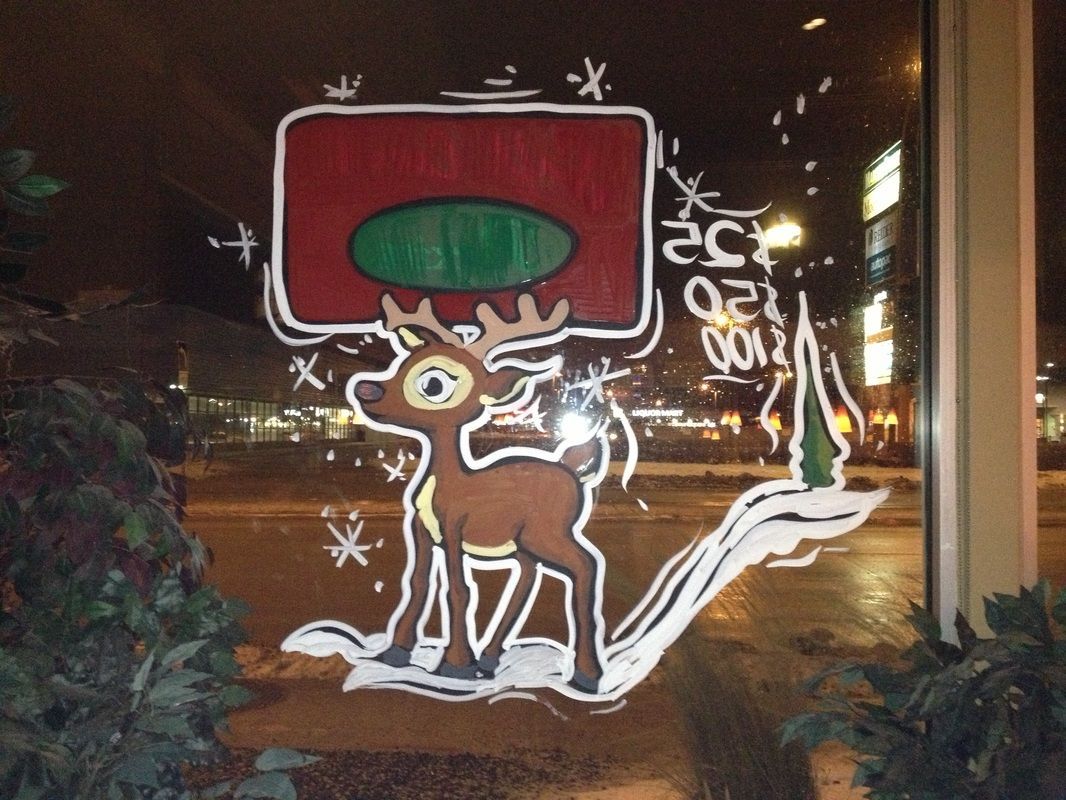 A drawing of a reindeer holding a christmas tree on a window