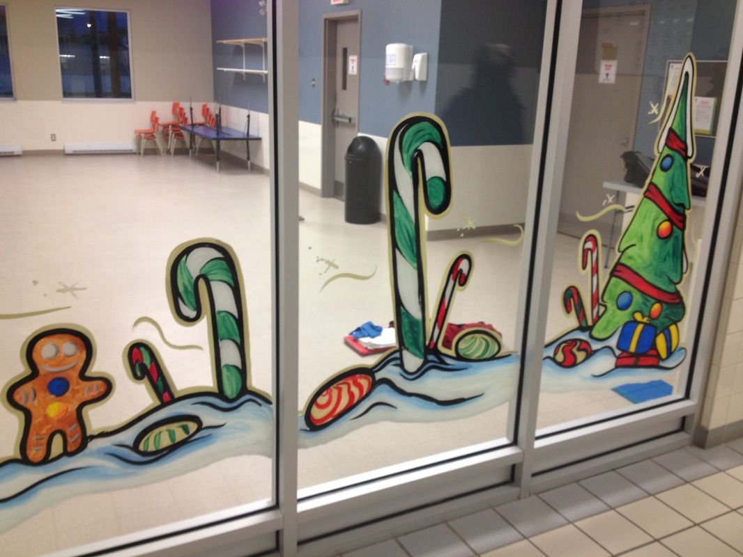 A window with a gingerbread man candy canes and a christmas tree painted on it