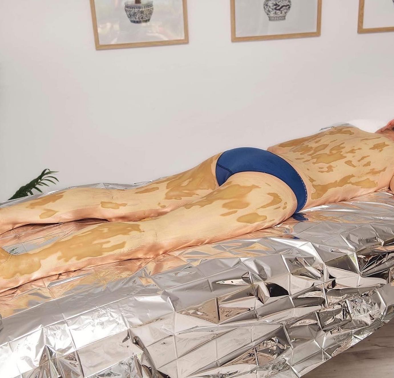 Person Lying on A Reflective Blanket, Body Covered in A Yellow Substance — Soul Good Beauty in Miami, QLD