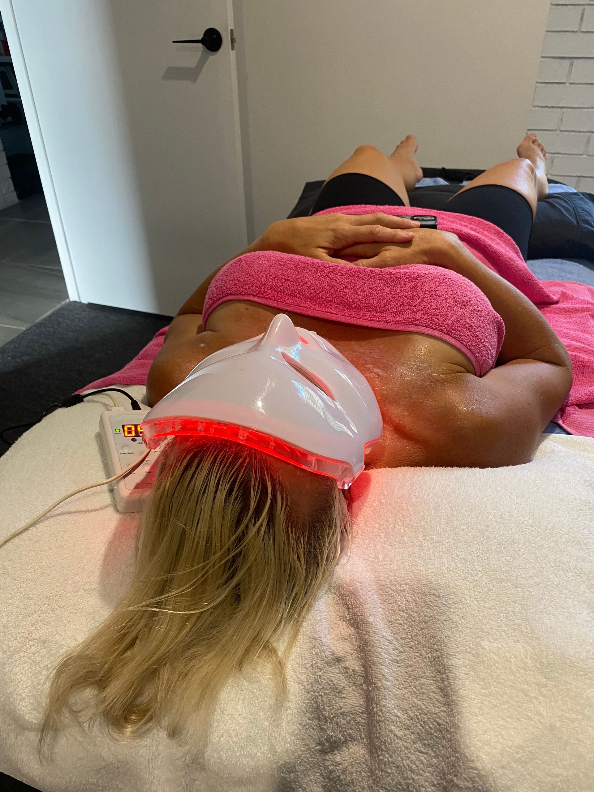 A technician uses a brush to apply a white facial mask onto a person lying on a treatment bed in a spa setting — Soul Good Beauty in Miami, QLD