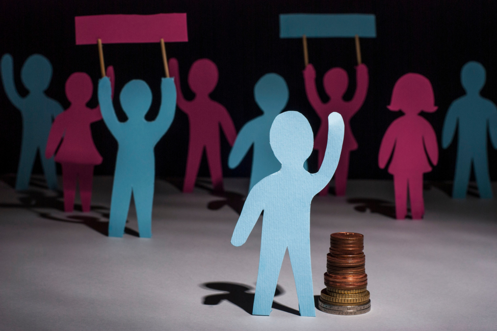 Blue and pink paper cutouts protesting, one in front of a stack of coins.