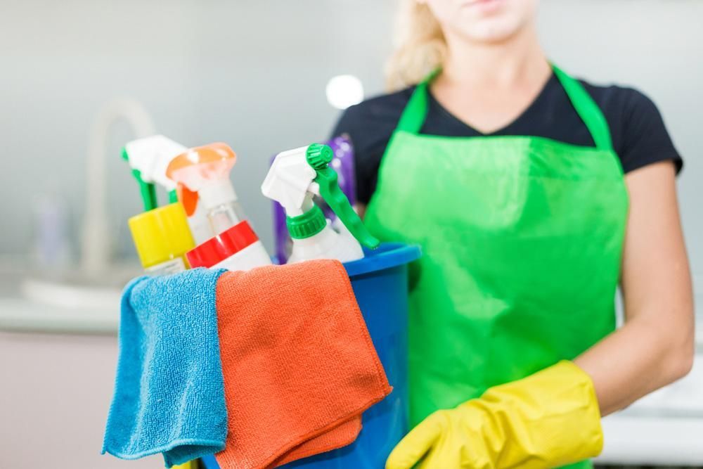 Woman in a Green Apron and Yellow Gloves is Holding a Bucket of Cleaning Supplies — Active Cleaning Service Rutherford, NSW