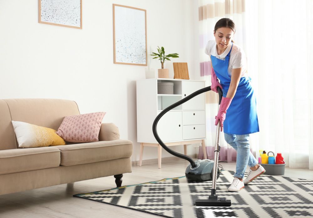 A lady vacuuming cleaning a rug in the lounge — Active Cleaning Service Maitland, NSW