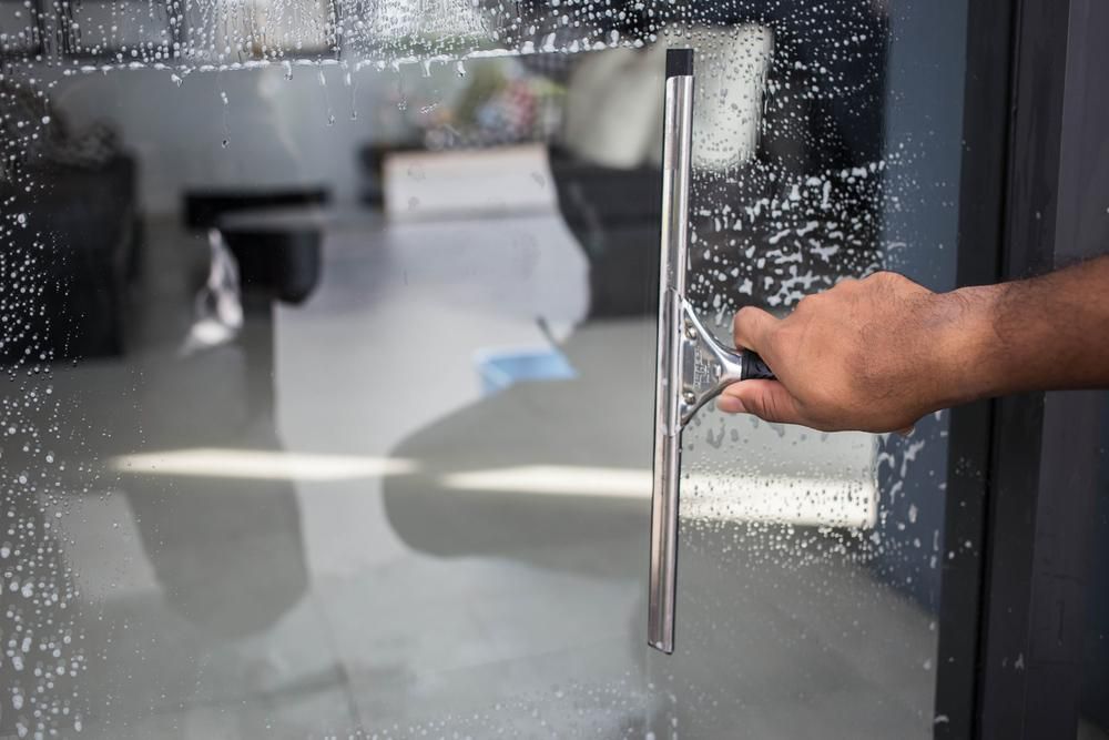 Person is Cleaning a Glass Door With a Squeegee — Active Cleaning Service Raymond Terrace, NSW