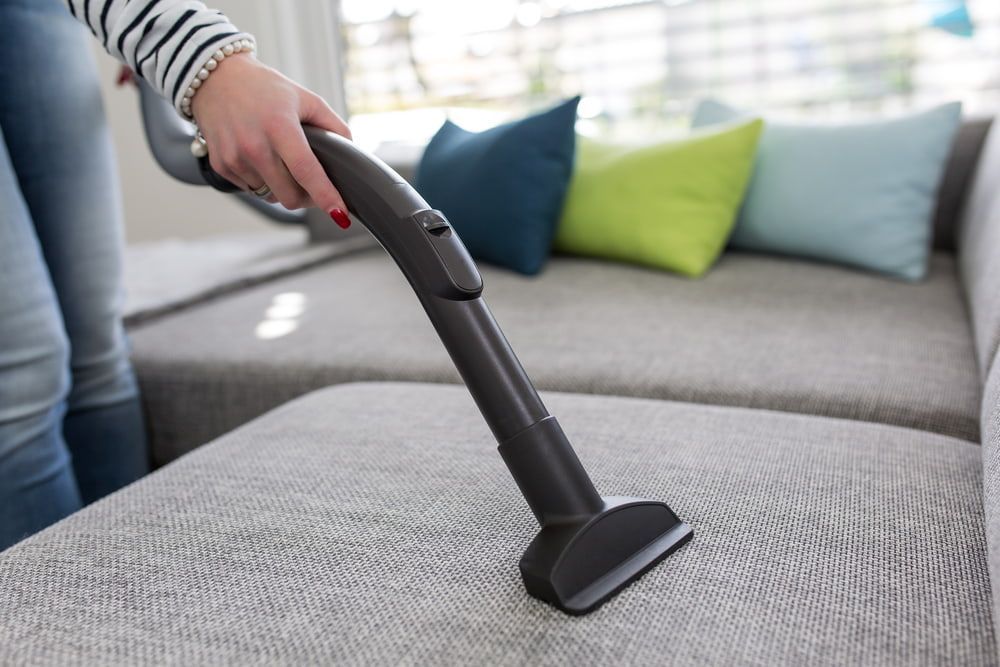 Woman is Cleaning a Couch With a Vacuum Cleaner — Active Cleaning Service Rutherford, NSW