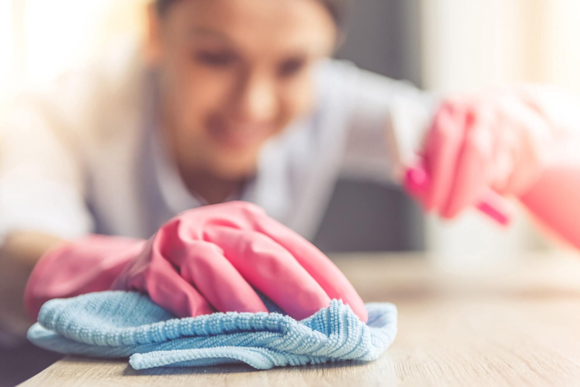 Woman in Pink Gloves is Cleaning a Table With a Cloth and Spray Bottle — Active Cleaning Service Newcastle, NSW