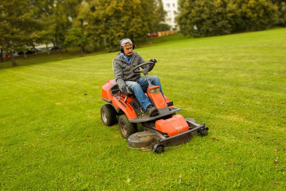 Man is Riding a Lawn Mower on a Lush Green Field — Active Cleaning Service Maitland, NSW