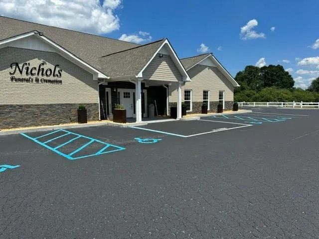 Nichols Funeral Home building with empty parking lot and blue handicap spaces under a sunny sky