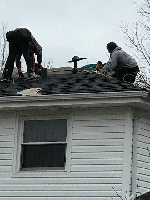Two men are working on the roof of a house.