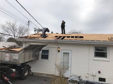 A group of people are working on the roof of a house.