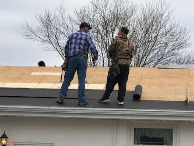 Two men are working on the roof of a house.