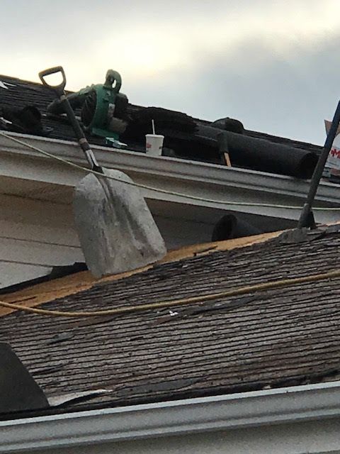 A shovel is sitting on the roof of a house.