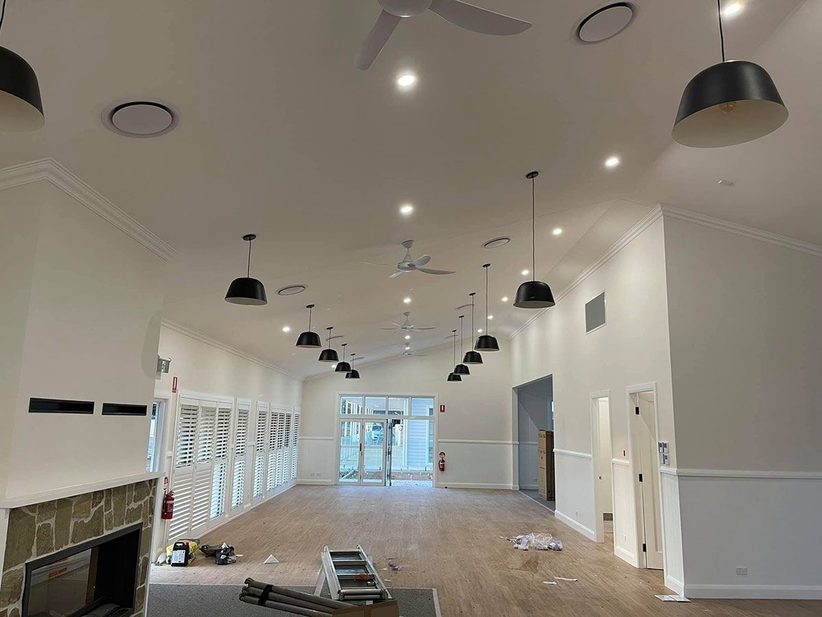 A Large Empty Room With A Fireplace And Ceiling Fan — Aircon Mid North Coast in Coffs Harbour, NSW