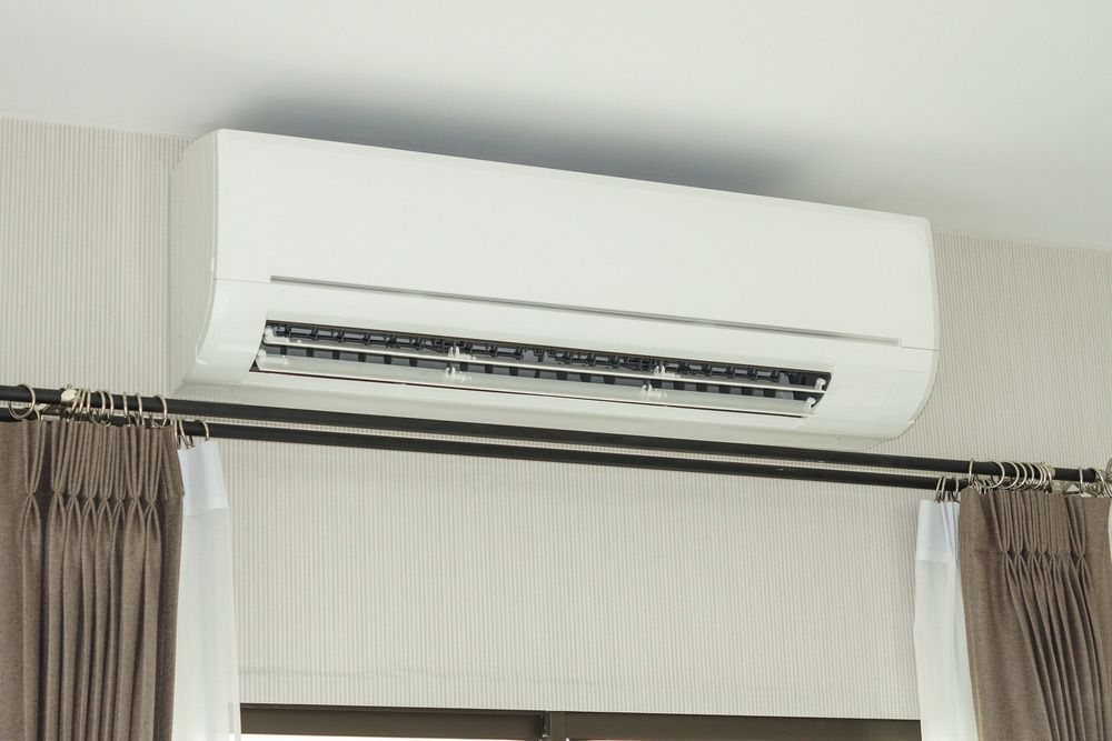 A White Air Conditioner Is Mounted To The Ceiling Above A Window — Aircon Mid North Coast in Newcastle, NSW
