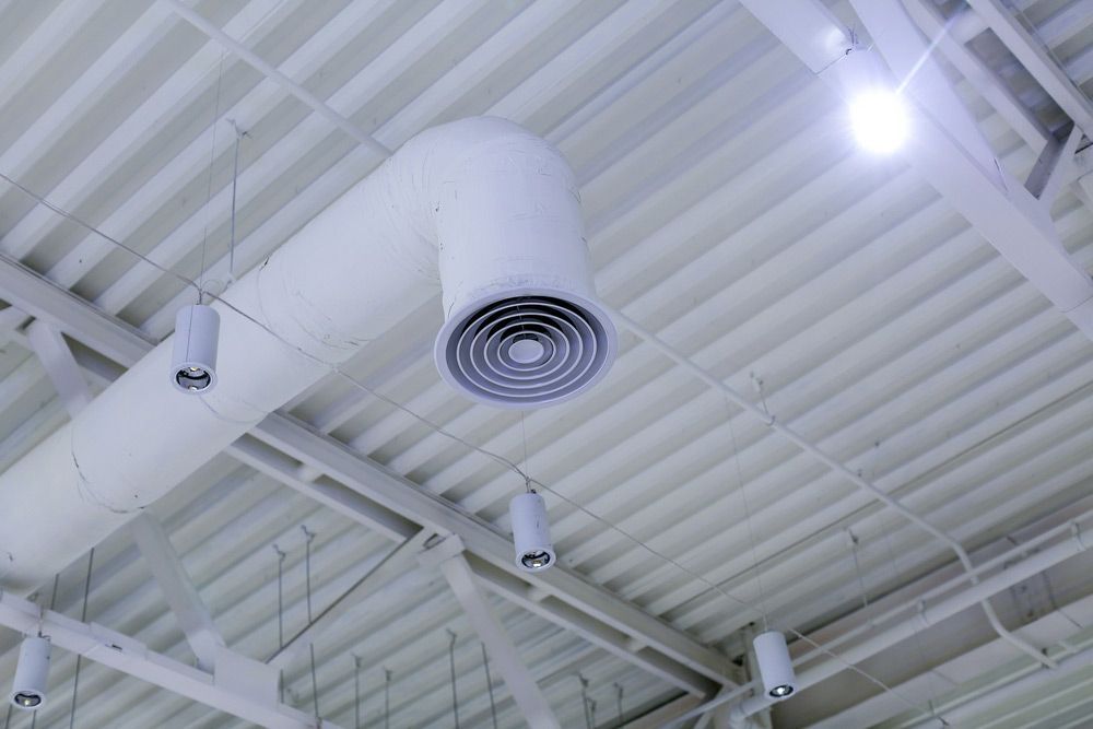 A White Air Duct Is Hanging From The Ceiling Of A Building — Aircon Mid North Coast in Taree, NSW