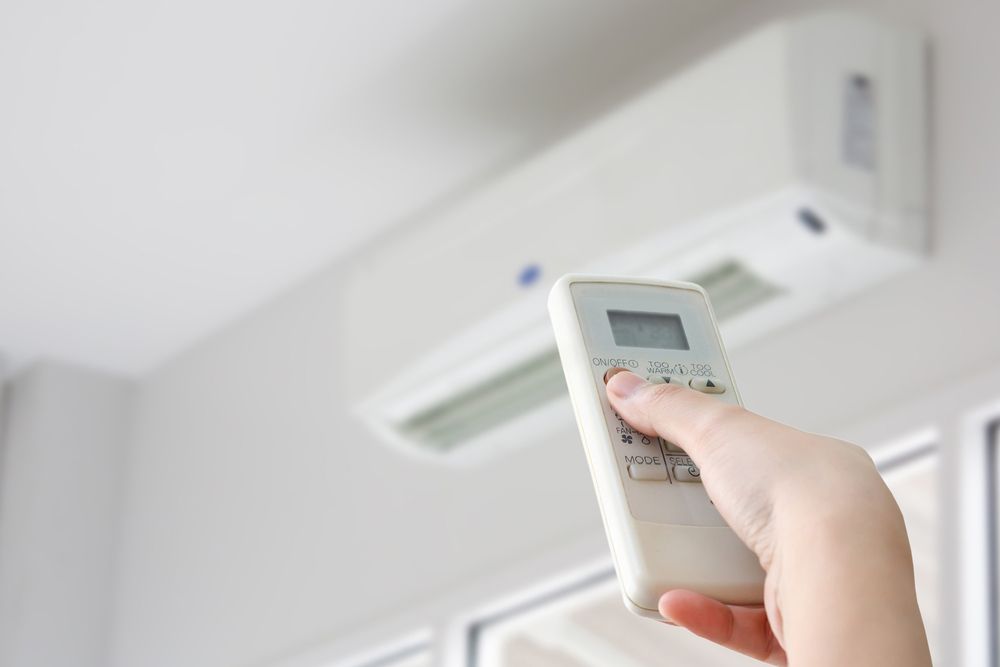 A Person Is Holding A Remote Control In Front Of An Air Conditioner — Aircon Mid North Coast in Coffs Harbour, NSW